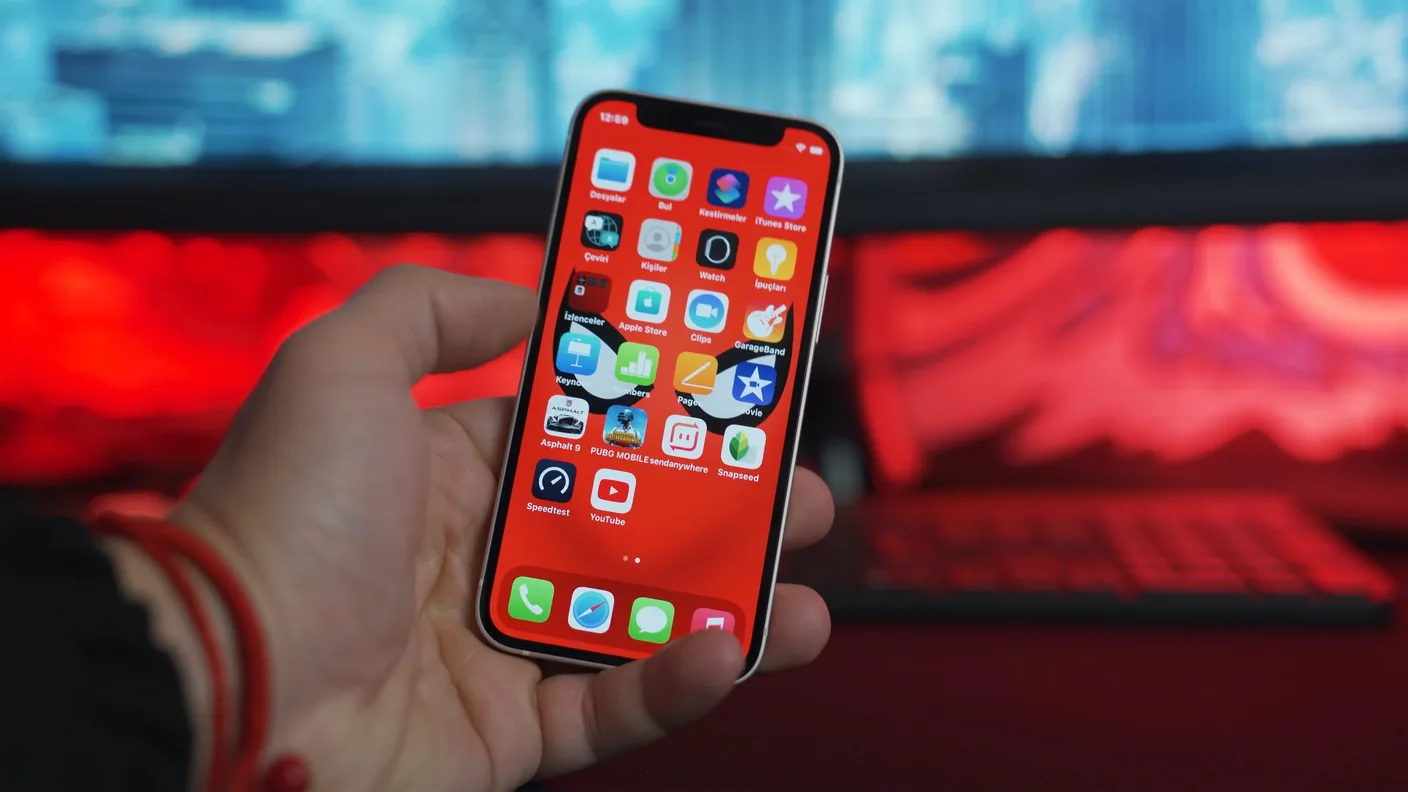 Hand met een smartphone vol app-iconen op het beginscherm
